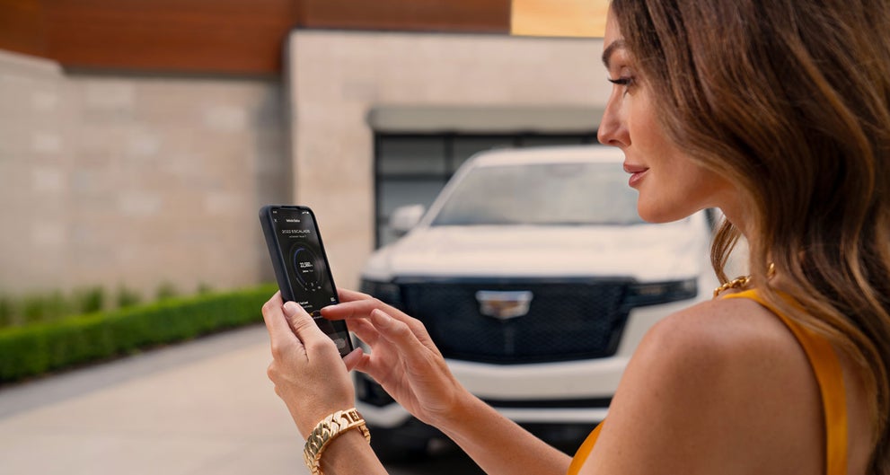 lady checking her mobile with a Cadillac vehicle background | Bommarito Cadillac in Saint Peters MO